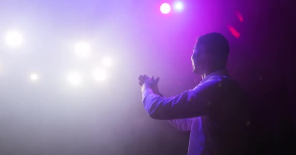 Showman-Komiker klatscht auf der Bühne in die Hände und unterhält Publikum im Scheinwerferlicht. — Stockvideo