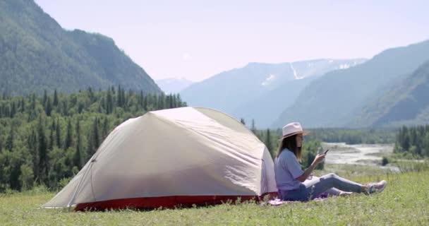 Donna escursionista è seduto sulla montagna vicino tenda e fare foto su smartphone. — Video Stock