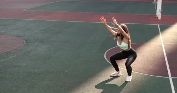 Passform ung kvinna tränar gör knäböj på stadion i College campus, träning. — Stockvideo
