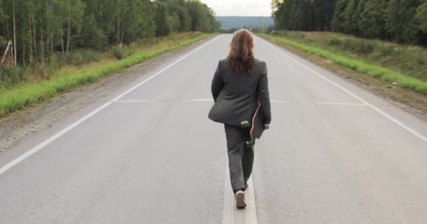 Hombre en traje de oficina con longboard en las manos caminando por la calle fuera de la ciudad. — Vídeos de Stock