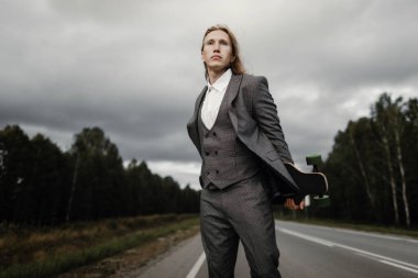 Ofis kıyafetli yakışıklı adam şehrin varoşlarında uzun bir yolda yürüyor..