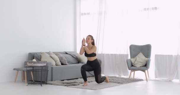 Sportowa młoda kobieta trenuje i wykonuje skok do domu w salonie. — Wideo stockowe
