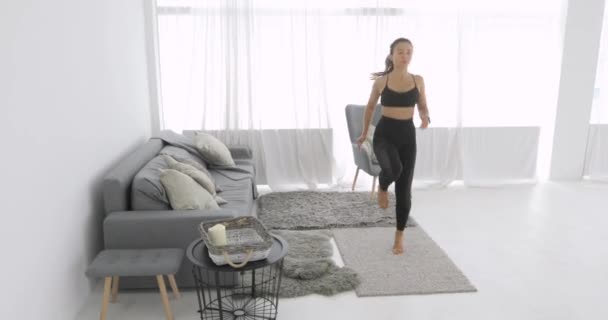 Jeune femme sportive court en place et s'entraîne à la maison, caméra en mouvement. — Video