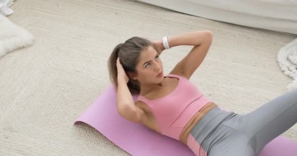Smal atletisk kvinna gör magövningar crunches på golvet hemma. — Stockvideo