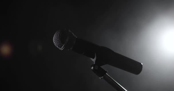 Nahaufnahme am professionellen Konzertmikrofon auf der Bühne im Scheinwerferlicht im Dunkeln. — Stockvideo