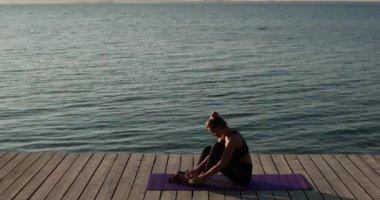 Kadın çoraplarını giyip yazın nehir rıhtımında spor paspasına oturuyor..
