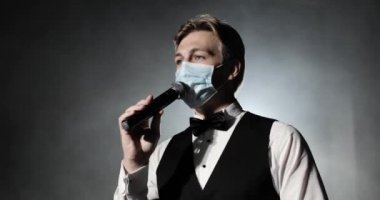 Medikal maskeli sunucunun portresi konserde mikrofonda konuşuyor..