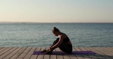 Kadın ayaklarına çorap geçirir nehir kıyısındaki paspasın üstüne oturur, yan gözle bakar..