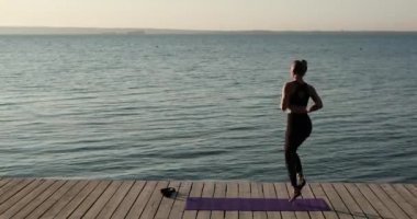 Kadınlar yazın nehir rıhtımında spor paspasında ısınıyor ve koşuyor..