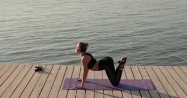 Genç kadın paspasın üzerinde esnek sırt ve yan görüş egzersizleri yapıyor..