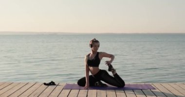 Kadın yoga yapıyor ve güvercin pozu veriyor nehir rıhtımında, yan gözle..