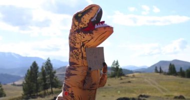 İçinde insan olan dev bir dinozor bebeği pankart tutuyor. Dünyayı pençeleriyle kurtarıyor..