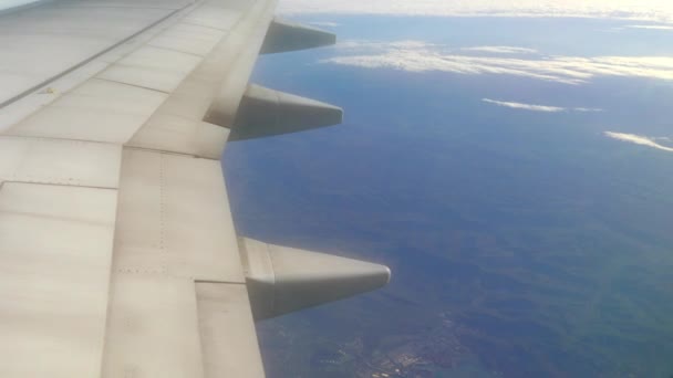 Крило літака, що летить над білими пухнастими хмарами на великій висоті — стокове відео