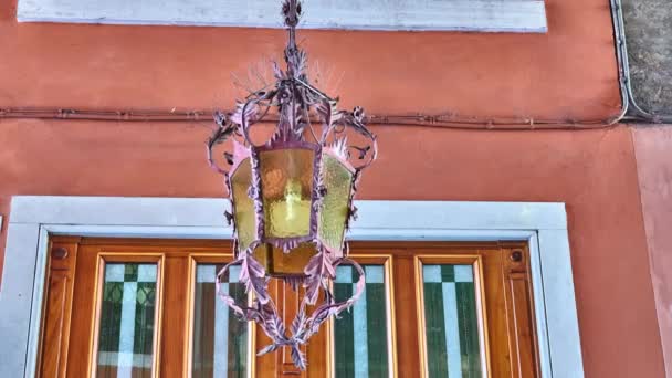 Cinemagraph loop: hängande lampa hänger i bågen till gamla byggnaden och svänger i vinden — Stockvideo