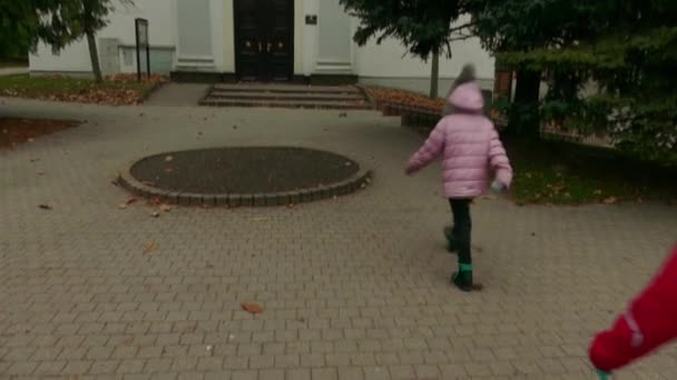 Due belle bambine camminano vicino alla Chiesa Evangelica della Santissima Trinità in Namestie Egidia Street, Poprad, Slovacchia . — Video Stock