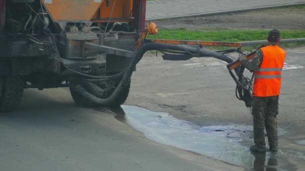 Trabajadores de la construcción reparando agujeros en la carretera con grava y betún con la ayuda de equipos especiales . — Vídeo de stock