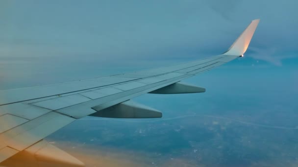 Крыло летающего самолета на фоне горизонта неба. Вид из иллюминатора . — стоковое видео