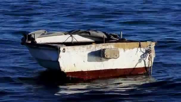 Старий човен гойдається на хвилях біля морського узбережжя . — стокове відео
