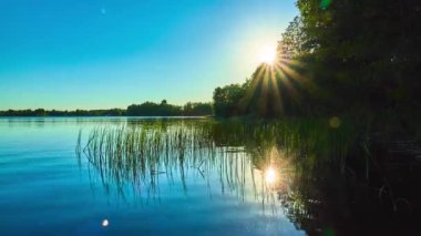 Arka planda ormanlık kıyıları ile büyük göl günbatımı.