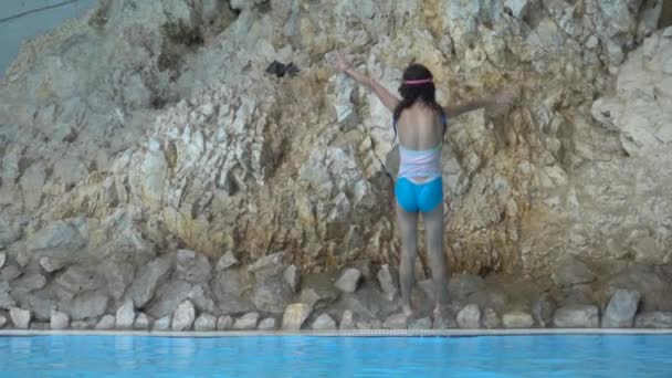 Movimento lento: Pequena menina bonita pulando na piscina com água limpa . — Vídeo de Stock