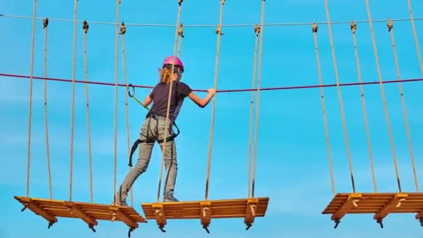 Chica escalada en el parque de aventuras es un lugar que puede contener una amplia variedad de elementos, tales como ejercicios de escalada de cuerdas, pistas de obstáculos y tirolesas . — Vídeos de Stock
