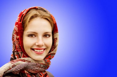 Genç kadın başörtüsü mavi arka plan üzerinde sevimli gülümseyen portresi.