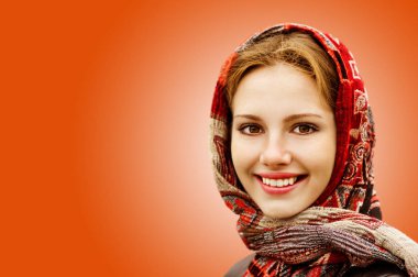 Turuncu zemin üzerine izole başörtüsü gülümseyen sevimli genç kadın portresi.