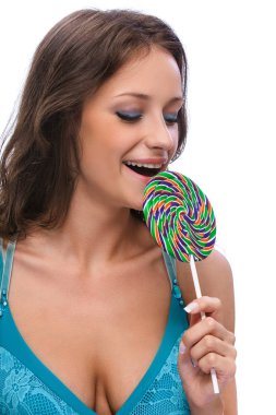 Lolipop şeker, beyaz arka plan üzerinde izole mavi elbiseli koyu saçlı genç gülümseyen güzel kadın portresi.