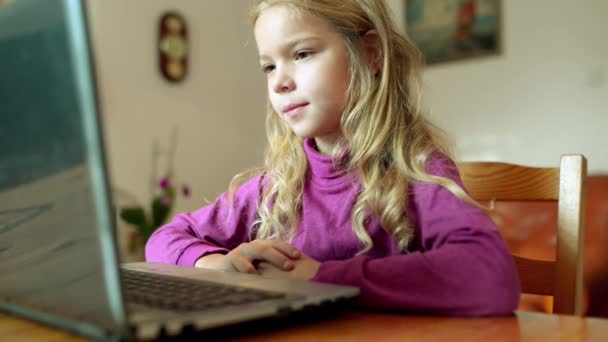 Όμορφη ξανθιά νεαρή κοπέλα που τρέχει σε μοβ μπλούζα εργάζεται για laptop στο μεγάλο δωμάτιο. — Αρχείο Βίντεο