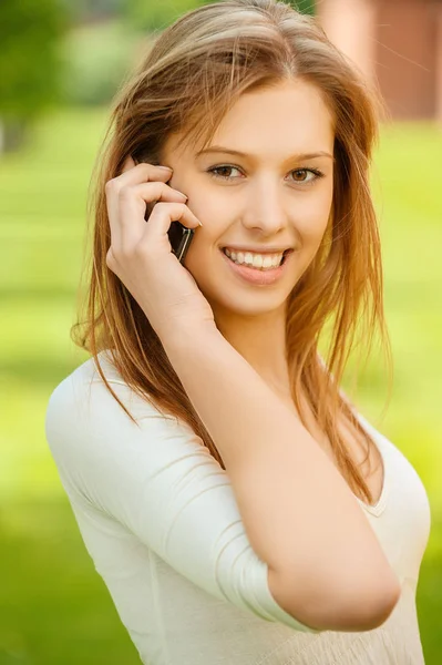 Uma bela jovem mulher em um vestido branco falar no telefone móvel — Fotografia de Stock
