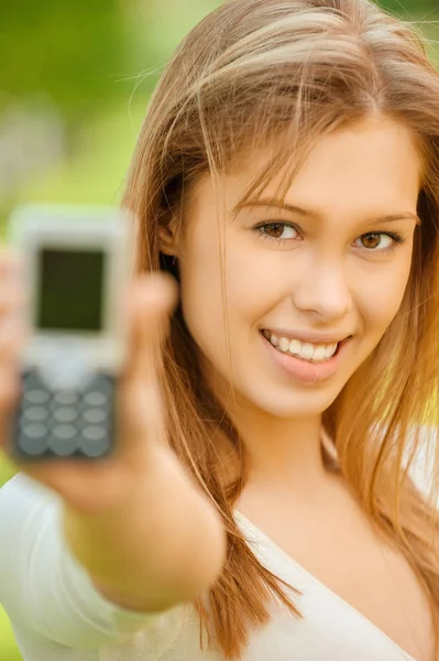 Eine schöne junge Frau im weißen Kleid zeigt ihr Handy — Stockfoto