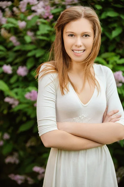 Una bella giovane donna vestita di bianco in mezzo ad un albero fiorito — Foto Stock