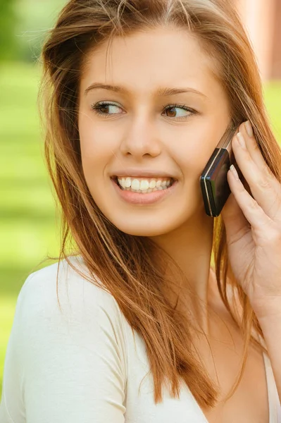 A beautiful young woman in a white dress speak on mobile phone — Stock Photo, Image