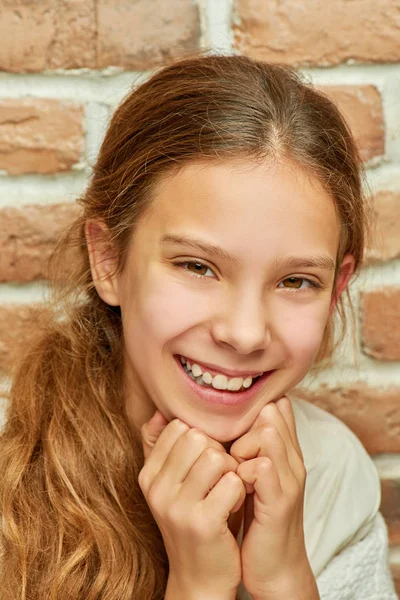 Adolescente com cabelos longos sorrindo contra a parede — Fotografia de Stock