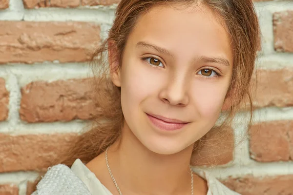 Krásná usměvavá holčička poblíž cihlová zeď — Stock fotografie