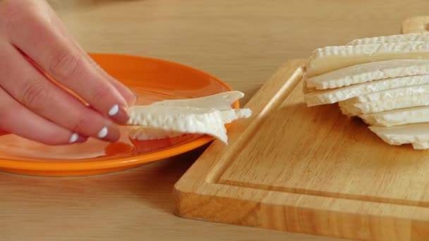 妇女将费塔奶酪从棋盘转移到盘子上 — 图库视频影像