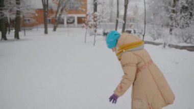 bej ceketli küçük güzel kız kartopu heykelve kış şehir parkı onları atar