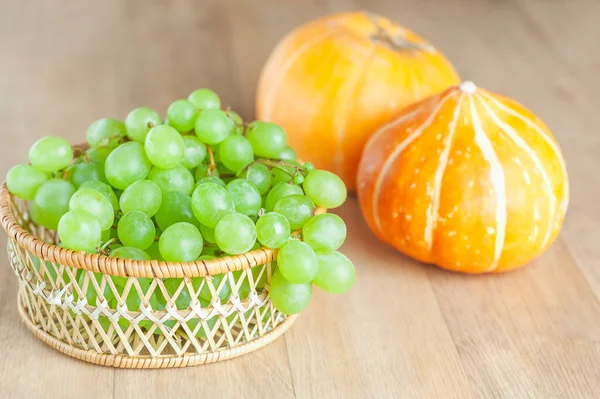 Hasır Sepetteki Yeşil Üzümler Ahşap Masada Iki Sarı Balkabağı — Stok fotoğraf