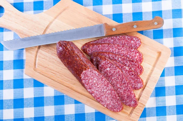 Wurst Und Messer Auf Einem Schneidebrett Auf Einer Karierten Blauen — Stockfoto