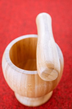 Kırmızı yün halıya ahşap havan ve tokmak..