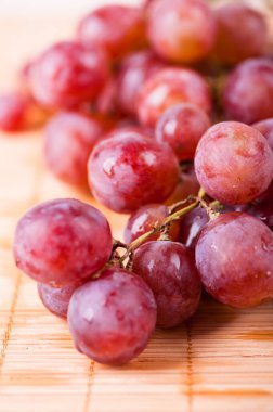Islak pembe üzümler bambu masa örtüsünde yatıyor..