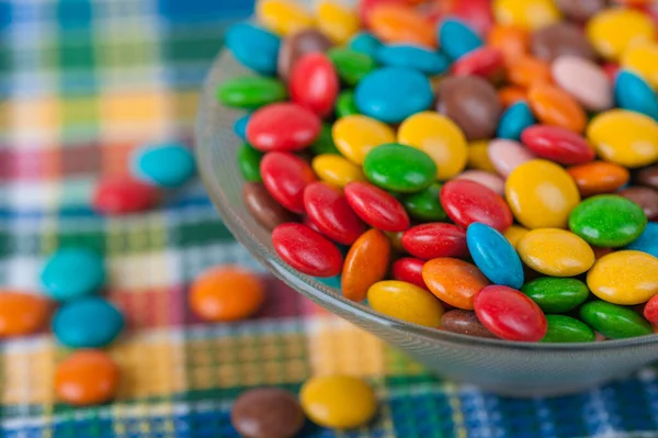 カラフルな小さなお菓子をボウルに入れ チェックされたテーブルクロスに — ストック写真