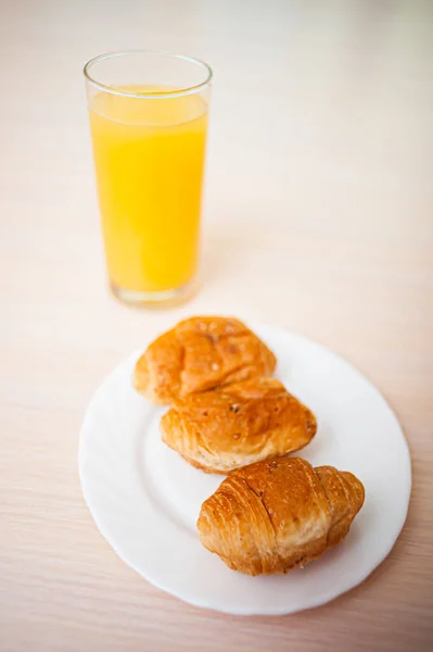 Čerstvé Croissanty Bílém Talíři Sklenici Pomerančového Džusu Stole — Stock fotografie