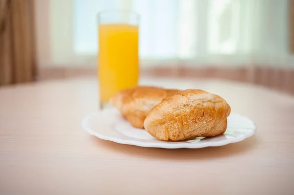Färska Croissanter Vit Tallrik Och Ett Glas Apelsinjuice Bordet — Stockfoto