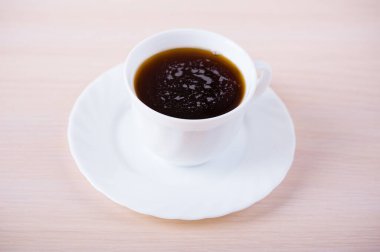 Bir fincan koyu siyah çay masanın üstünde duruyor..