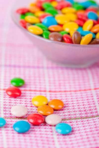 カラフルな小さなお菓子で黄色のボウルにザ赤チェッカードテーブルクロス — ストック写真