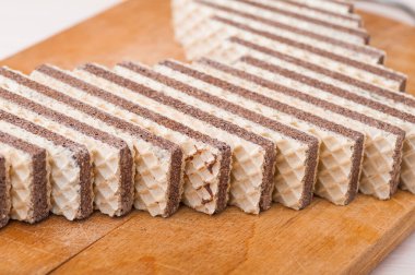 Uzun dikdörtgen çikolatalı gofretler tahta bir kesme tahtasının üzerinde yatıyor..