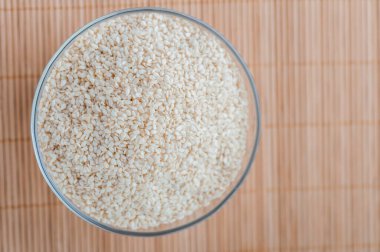 Bambu masa örtüsünde beyaz susam tohumlu cam kase..