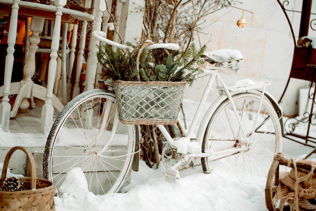 White bicycle with a basket with fir branches outside, New Year's decoration for the holiday