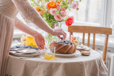 Çay saati, Kadın elleri elinde çaydanlık, çiçek ve kek